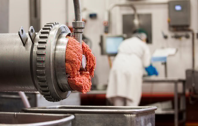 Kött kommer ut ur köttkvarn i fabrik