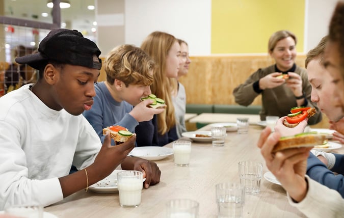 Ett grupp elever äter smörgåsar i skolrestaurangen.